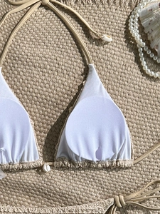 Detail of white crochet bikini top with seashell accents and removable pads on sand mat