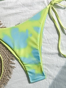 Detail der blau-grünen Tie-Dye-Bikinihose mit seitlichen Bändern auf weißem Stoff