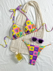 Flat lay detail of a vibrant mosaic print bikini with evil eye patterns and size S tag
