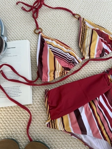 Two-piece striped bikini with neck strap and tortoise resin ring decoration on flat lay