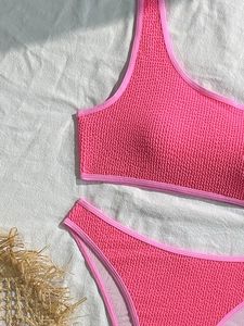 Detailed macro view of vibrant pink textured fabric on a two-piece bikini set