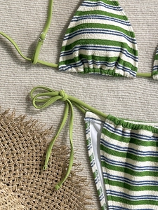 Close-up of textured striped bikini fabric with halter neck strap and metal ring detail