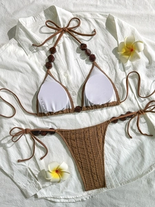 Brown knit halter bikini set with wooden beads displayed on white fabric background