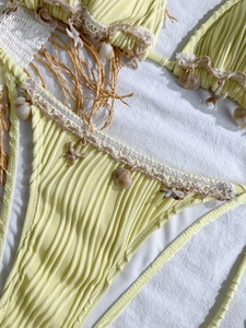 Detail of yellow ribbed bikini with crochet trim, natural seashells, and starfish charms