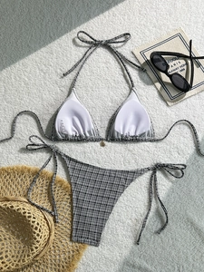 Chic black and white gingham bikini set with halter top and side-tie bottoms on a beach setup