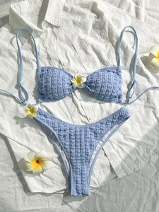 Detail of light blue seersucker bikini fabric with textured waffle pattern and plumeria flower