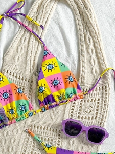 Detail of colorful bikini top with eye print and wash label on beige crochet bag
