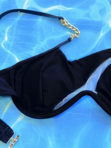 Detail eines schwarzen Bikini-Tops mit eleganten goldmetallenen Ketten und Schnalle