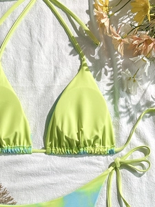 Detail eines neongrünen Tie-Dye-Bikini-Oberteils mit Neckholder und Faltenstruktur