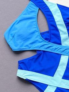 Detail of color-block one-piece swimsuit featuring asymmetric cutouts and patchwork design