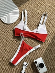 Sexy contrast red and white split bikini set with high-cut bottoms on a rustic beach mat