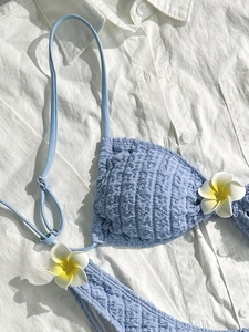 Detail of light blue smocked bikini set with delicate 3D plumeria flower decorations