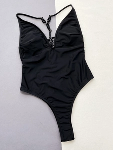 Détail d'un maillot de bain noir avec décolleté en V plongeant et anneaux métalliques argentés