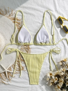 Close-up of ribbed texture light green bikini with starfish and straw hat on white fabric