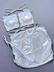 Flat lay of a three-piece metallic silver bikini set including top, thong and mini skirt