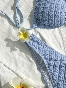 Detail of light blue textured bikini set with floral accent and ruffle fabric