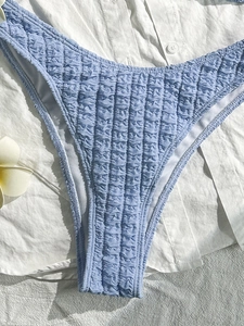Detailed macro view of light blue textured seersucker bikini bottoms with wavy hem design