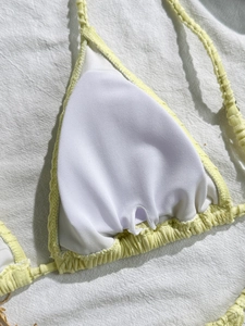 Detail of light yellow bikini top showing textured fabric and inner cup padding slot