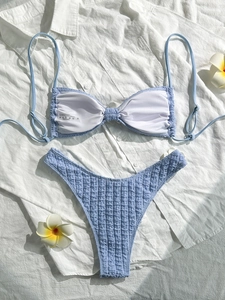 Close-up of light blue bikini set with bow top and textured high-cut bottom on fabric