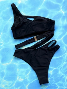 Detail of black one-shoulder bikini featuring a gold buckle and hollow-out waist cutouts