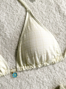 Detail of yellow gingham bikini top with ruched edges and blue daisy charm pendant