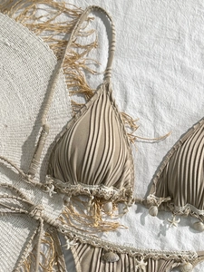Detail of seashell pendants and crochet trim on a textured ribbed bikini set