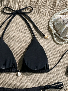 Detailed view of black bikini top with shell accents and woven fabric texture