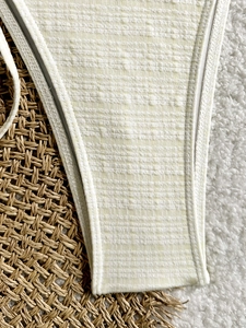 Detailed close-up of cream waffle-textured fabric on sexy bikini bottom waistline