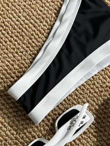Close-up of contrast stitching on black and white bikini with white sunglasses