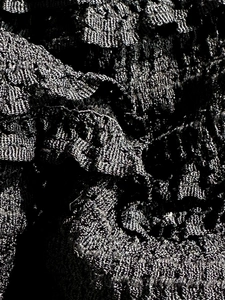 Macro detail of textured black fabric with metallic silver threads and crochet patterns