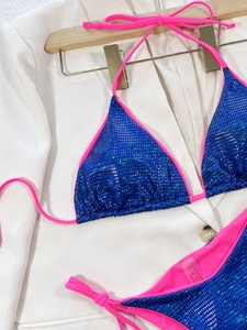 Dettaglio bikini in tessuto blu con paillettes e cinturini rosa con etichetta
