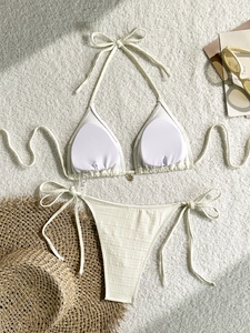 Detail of cream ribbed bikini top featuring a small metal flower pendant and halter ties