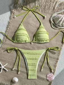 Detail of light green ruched bikini set with ruffled edges and white seashell tassels
