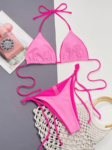 Flat lay of pink string bikini with summer props showing side-tie detail and fabric texture