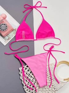Detail of hot pink bikini top with stitched size S laundry label on textured fabric