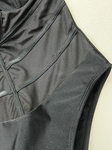 Close-up of black one-piece swimsuit featuring mesh panels and reinforced shaping seams