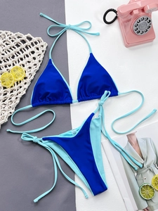 Flat lay of blue two-tone triangle bikini with side ties and summer vacation props