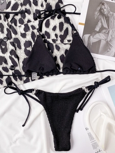 Close-up of black two-piece bikini featuring metallic ring details and textured seersucker fabric