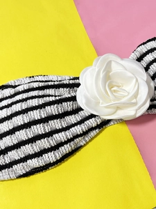 Detail of striped bikini top featuring a large 3D white rose on textured fabric