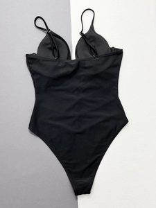 Detailed flat lay of black one-piece swimsuit with mesh panel and adjustable straps