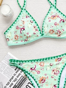 Mise à plat d'un bikini floral avec bords en coquille et lanières sur fond de plage