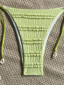 Detailed macro view of smocked green bikini bottom with ruffled edges and shell charms