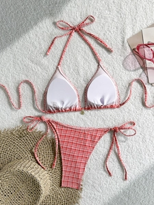 Flat lay of red and white gingham bikini set with straw hat and pink sunglasses