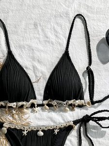Detailed view of black ribbed bikini with lace trim and natural shell charms