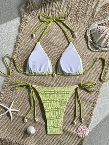 Detail of light green puckered fabric bikini with small white seashell accents and a size tag