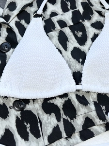 Detail of white seersucker bikini top with metal ring and leopard print background