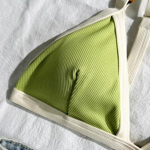 Detail eines gerippten Bikini-Oberteils in Grasgrün mit cremefarbenen Akzenten