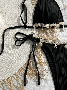 Detail of black ribbed bikini with crochet lace trim and seashell starfish charms