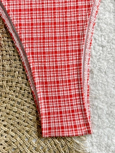Detailed macro view of red and white gingham bikini fabric with white double stitching
