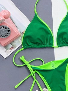 Detail of green bikini set showing material tags and high-quality nylon fabric texture